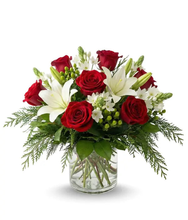 Bouquet of red roses and white lilies in a clear vase on a white background